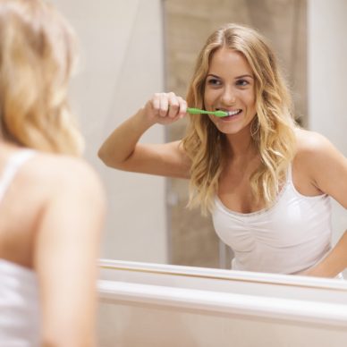 Woman brushing teeth in front of mirror