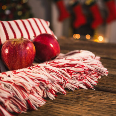 Rolled blanket with two apples on wooden table against christmas decor