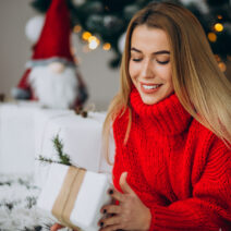 Young woman with christmas presents by the christmas tree