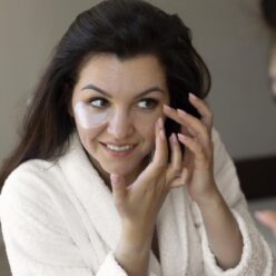 close-up-smiley-woman-applying-eye-patch (1)